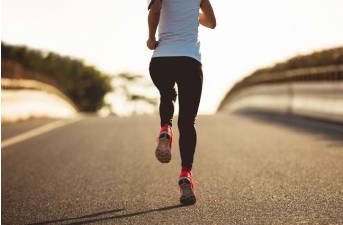 Seseorang sedang jogging di jalan saat matahari terbit, melambangkan gaya hidup sehat melalui olahraga.